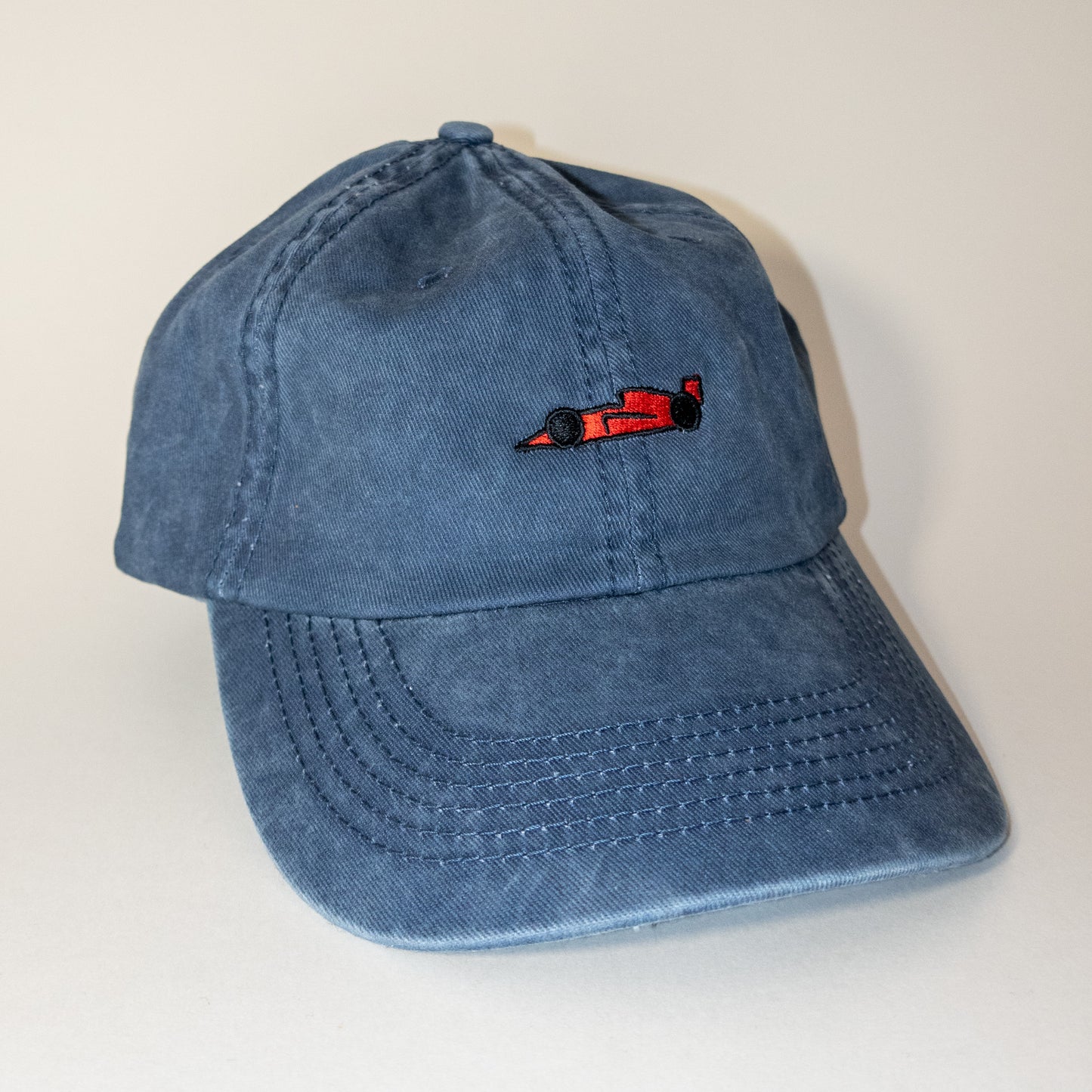 Red race car logo on washed blue hat